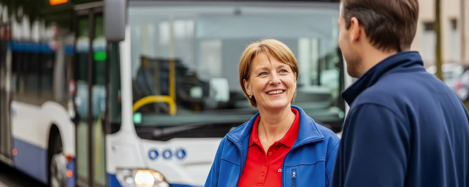 Eine lächelnde Frau in Nahaufnahme, im Hintergrund ein Bus.