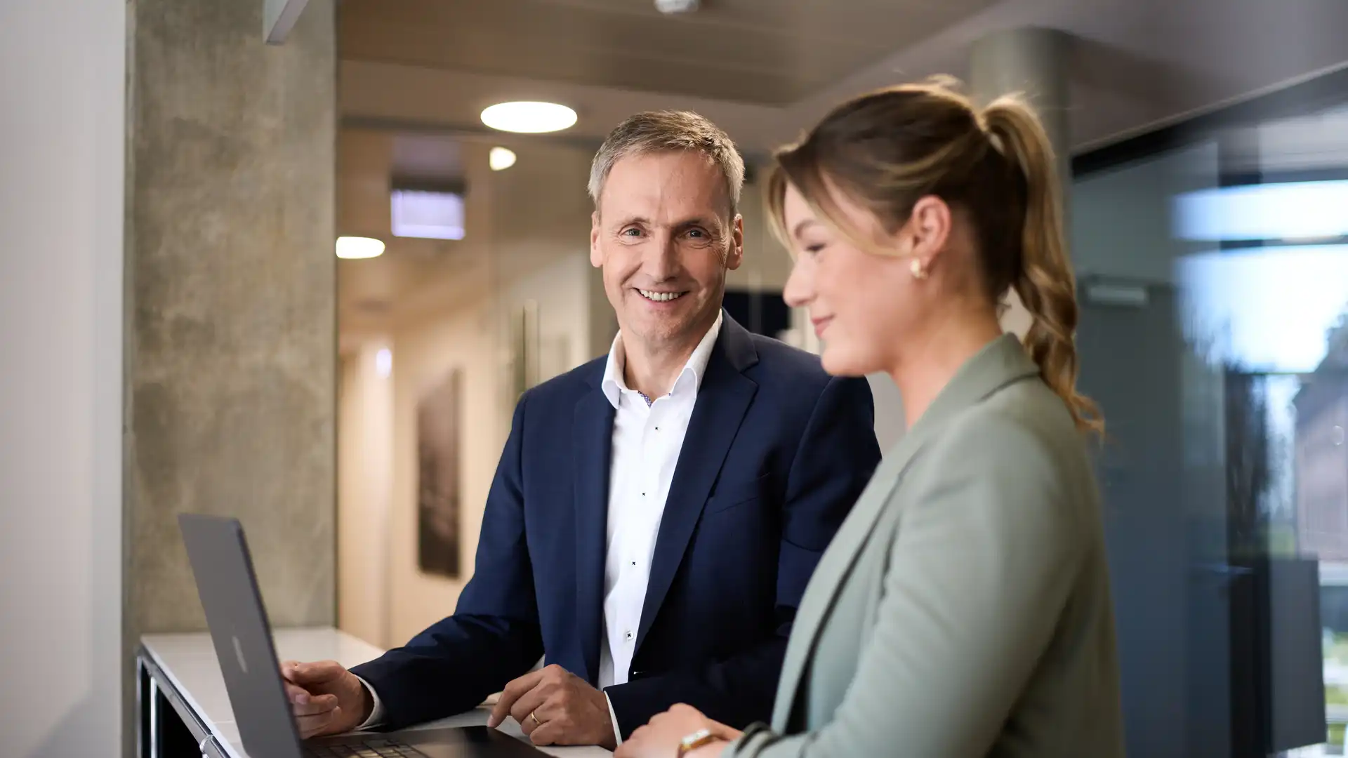 Eine Frau und ein Mann stehen an einem Tisch vor einem Laptop