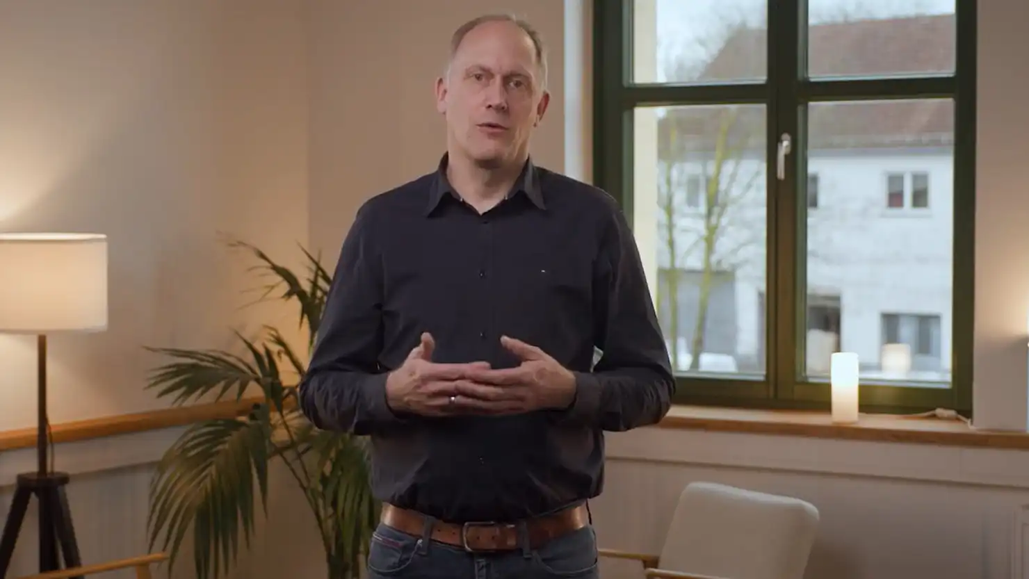 Ein Mann steht vor einer Sitzecke und referiert über Kryptowährungen im Steuerrecht