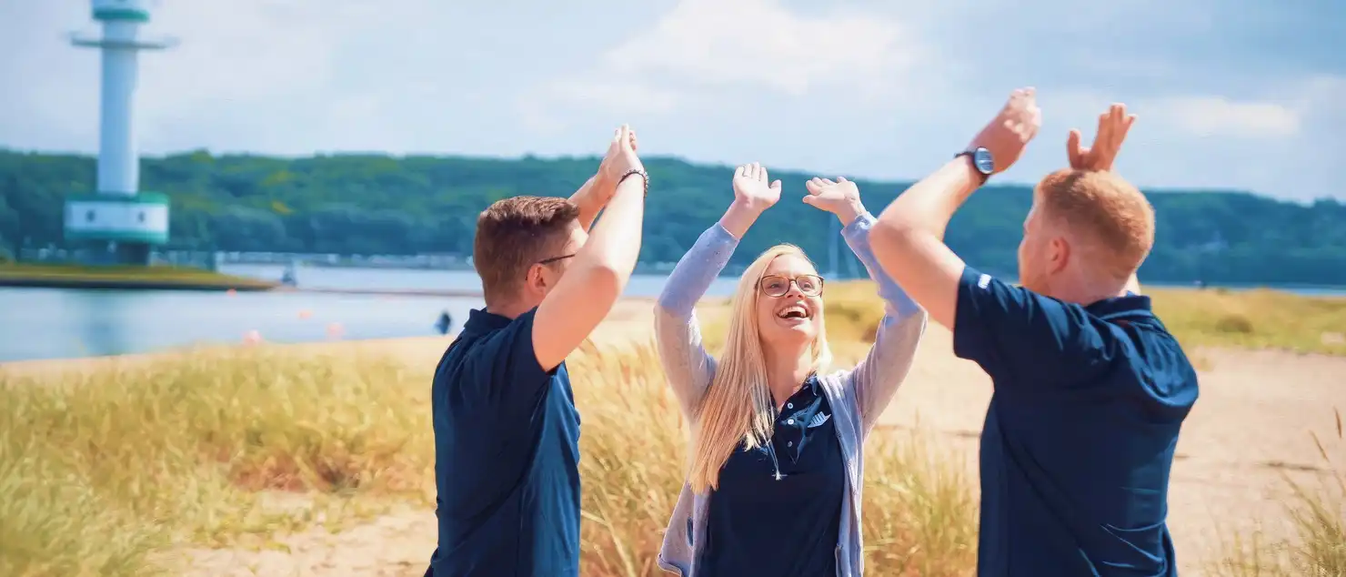 Drei Personen in blauen T-Shirts stehen auf einem Feld