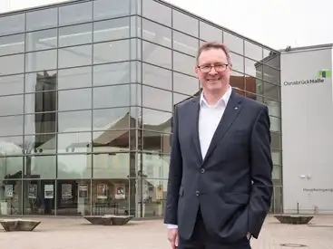 Andreas Alker vor einem verglasten Gebäude